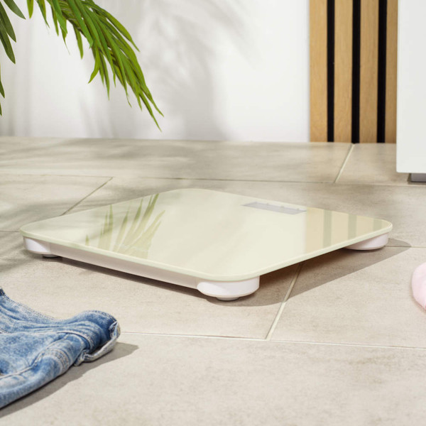 Cream digital bathroom scale on tiled floor, angled view, with jeans and pink top nearby