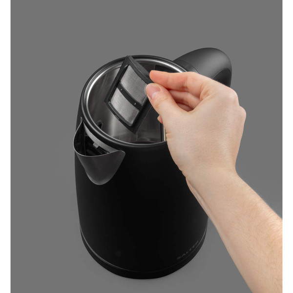 Hand removing limescale filter from black electric kettle