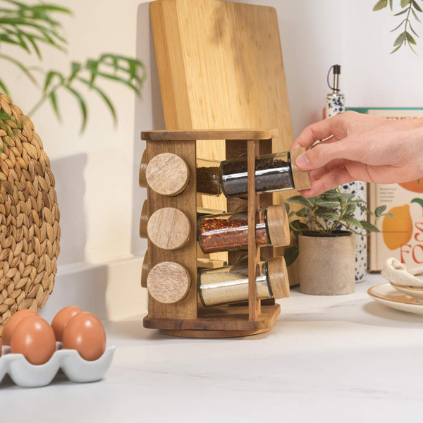 Wooden spice rack with twelve glass jars and wooden lids, plus one empty jar beside.