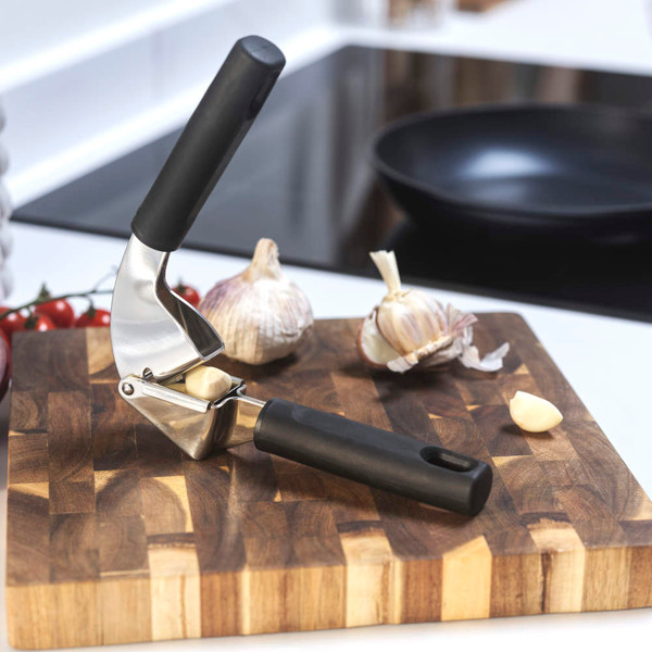 Stainless steel garlic press with black handles, shown closed on white background