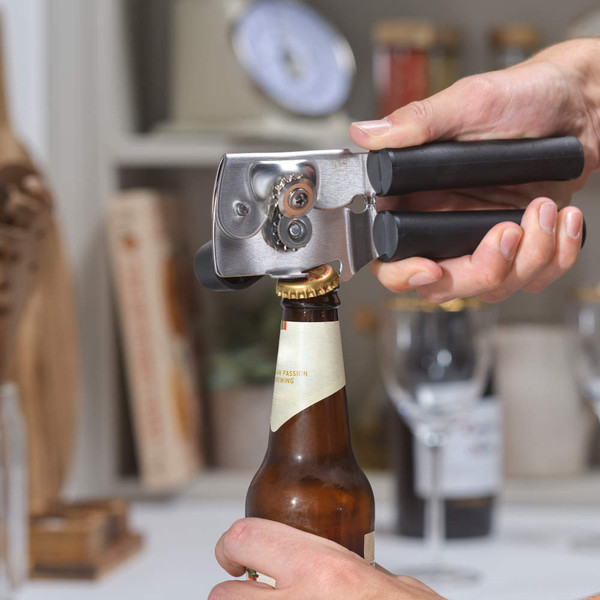 Black-handled bottle opener in use opening a beer bottle
