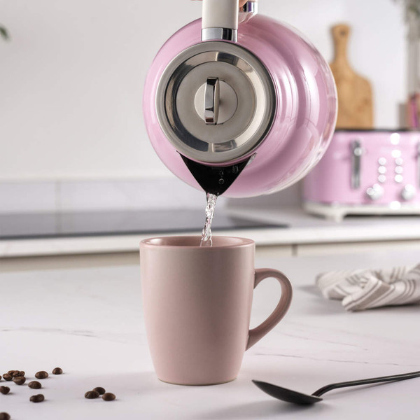 Pink kettle pouring hot water into matching mug on kitchen counter