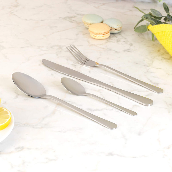 Set of four stainless steel cutlery pieces on marble surface