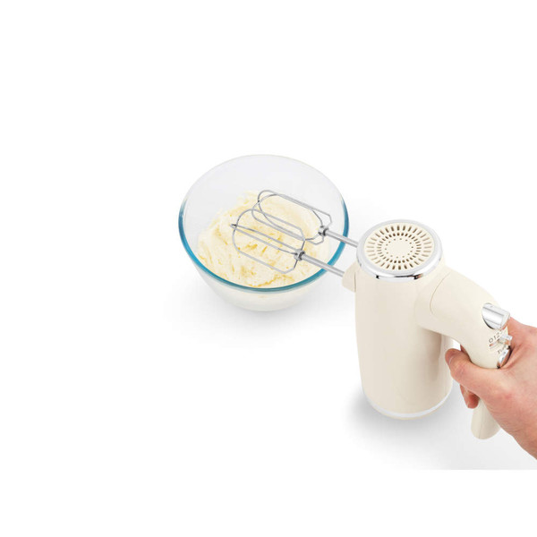 Cream hand mixer whipping cake batter in a glass bowl