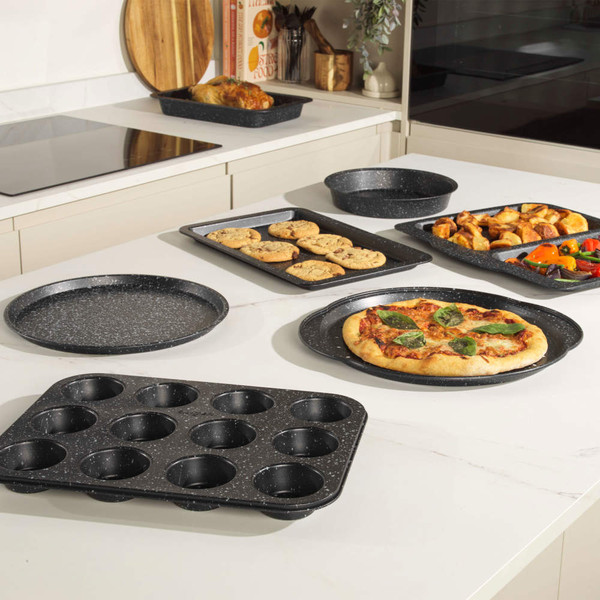 Non-stick black bakeware set shown with pizza, muffins, cookies, and roasted vegetables.