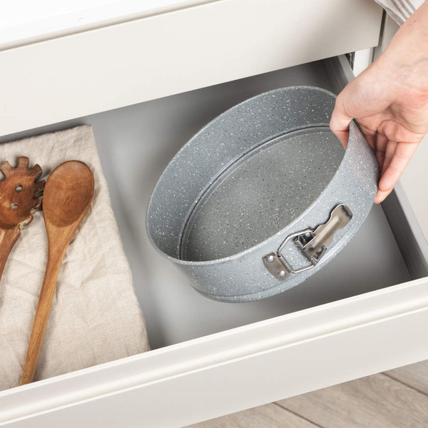 Grey non-stick cake tin with latch being placed in kitchen drawer