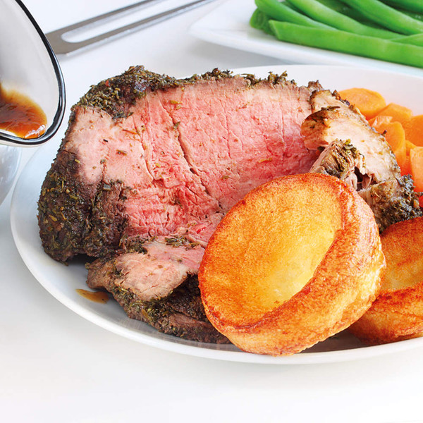 Roast beef with Yorkshire puddings, carrots and gravy on serving plate