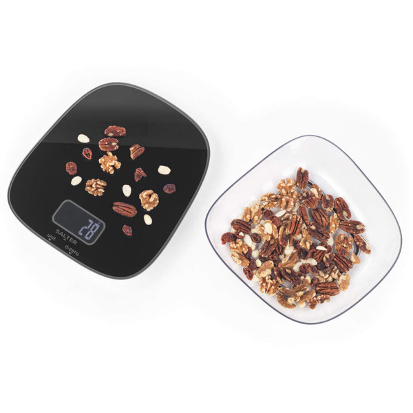 Black digital kitchen scale with assorted nuts on top, next to a bowl of mixed nuts