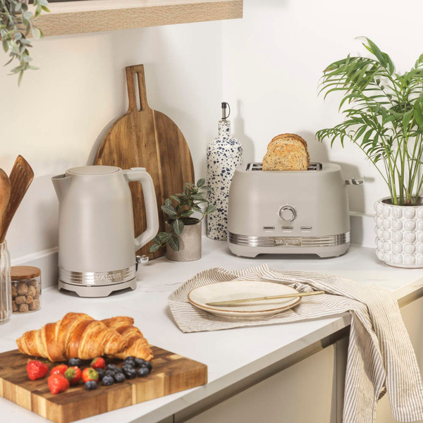 Taupe kettle and toaster set on kitchen counter with croissant and fruit breakfast.