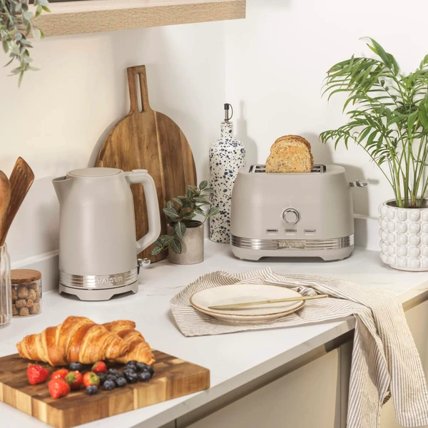 Taupe kettle and toaster set on kitchen counter with croissant and fruit breakfast.