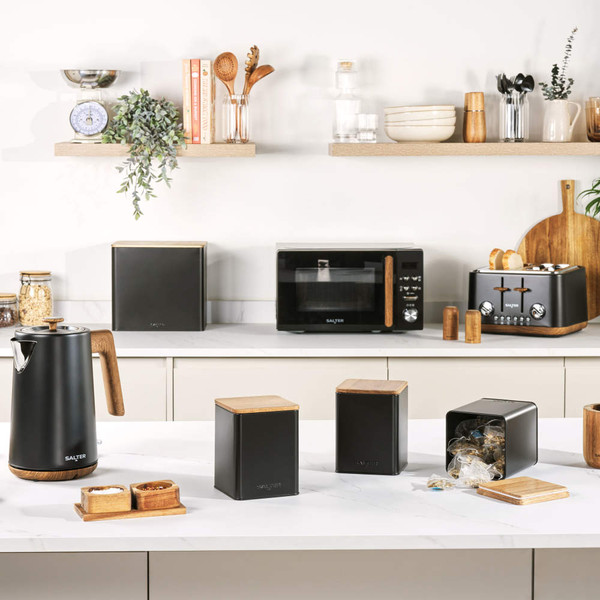 Black kettle, toaster, microwave and storage canisters with wooden accents on kitchen counter