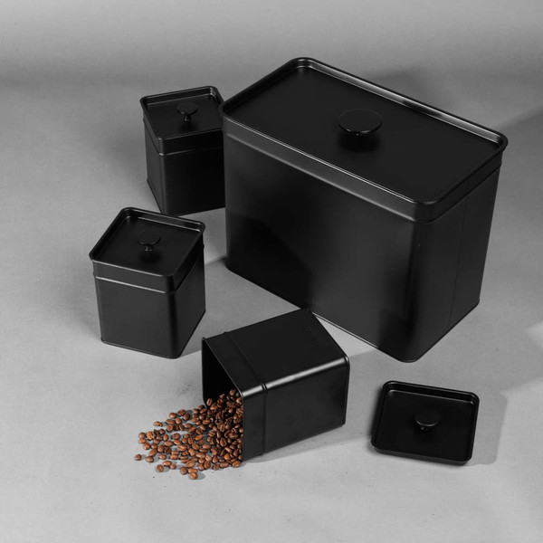 Set of black metal storage tins, one open with coffee beans spilling out