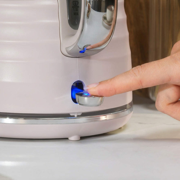Close-up of finger pressing the illuminated on switch on a pink electric kettle