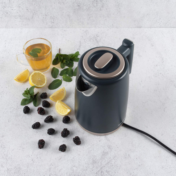 Grey electric kettle on worktop with fresh mint, lemon, blackberries and a glass of herbal tea