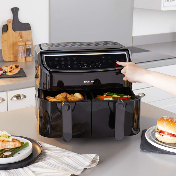 Black Salter dual air fryer in kitchen, both drawers cooking, with food served on plates nearby