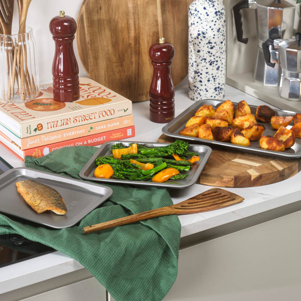Set of three grey non-stick roasting trays, nested, viewed from above.