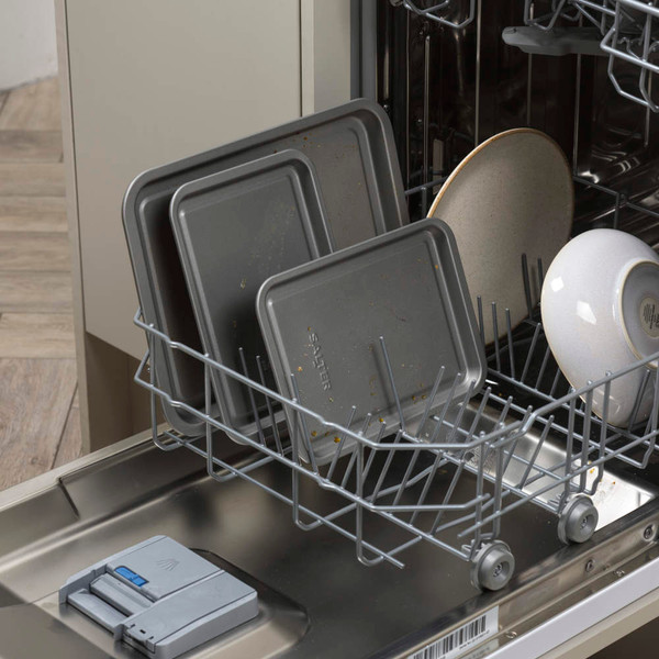 Grey baking trays and crockery in dishwasher lower rack