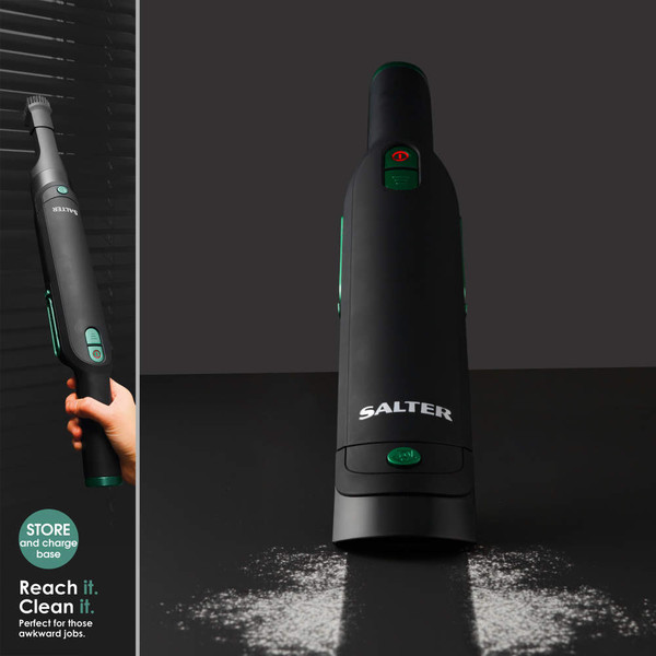 Black handheld vacuum cleaner with green buttons shown cleaning spill, Salter branding