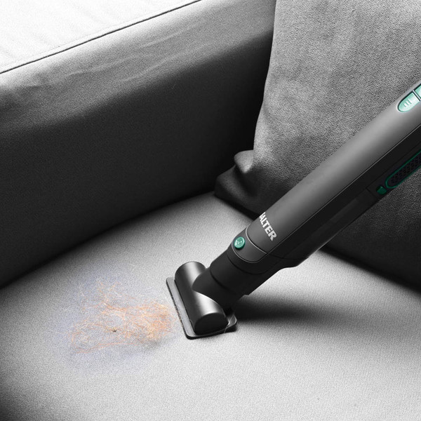 Handheld vacuum cleaning pet hair from grey fabric sofa seat cushion