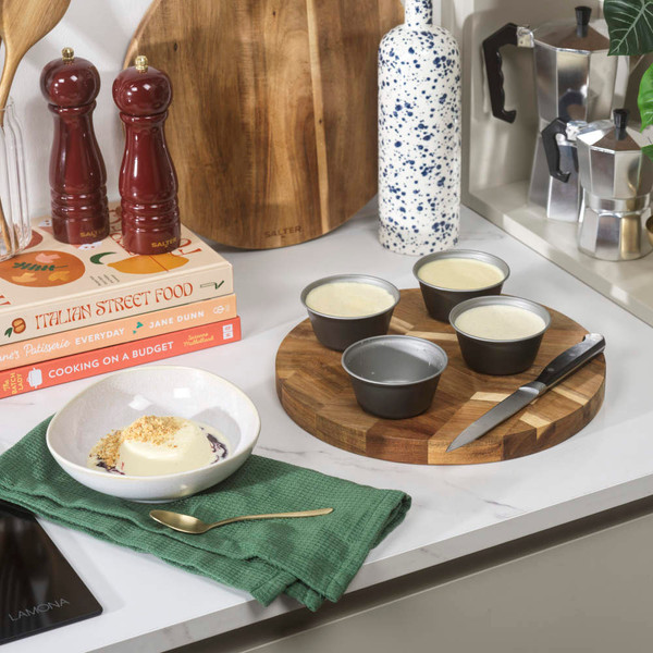 Set of four grey non-stick pudding moulds on kitchen worktop, suitable for baking