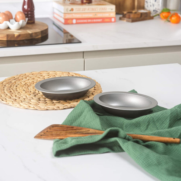 Two baked pies with golden crusts on a wooden board in a kitchen setting
