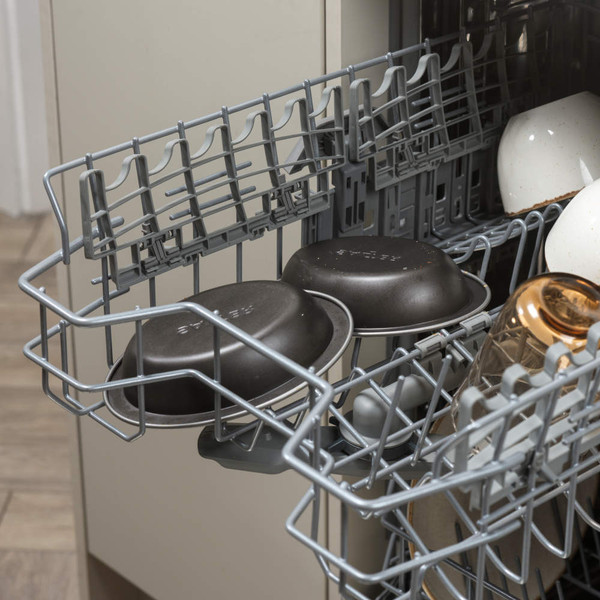 Grey baking tins positioned upside down in a dishwasher rack.