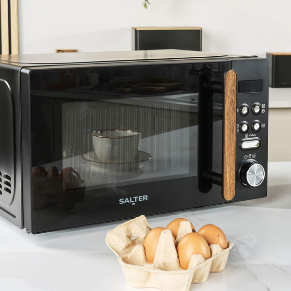 Black Salter microwave with wood-effect handle on kitchen counter, eggs in carton in foreground