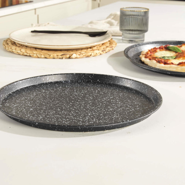 Black speckled round pizza tray shown empty on kitchen counter