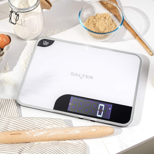 Salter white digital kitchen scale on worktop, display lit, with baking ingredients