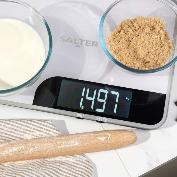 White Salter digital kitchen scale with bowls of milk and brown sugar, display reads 1.497kg.