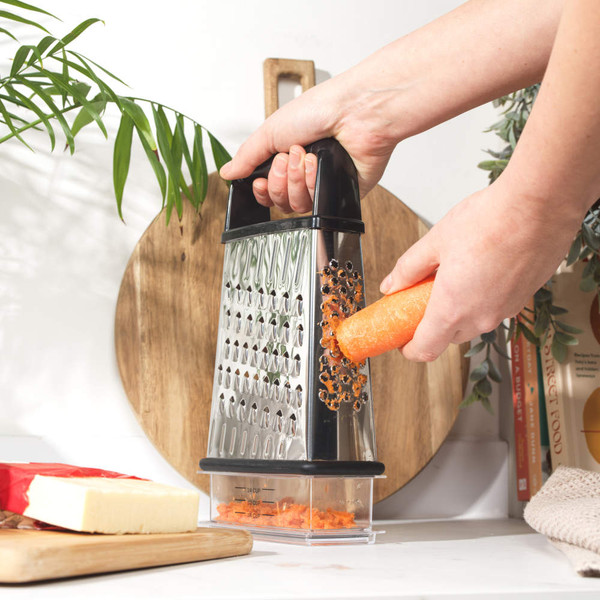 Stainless steel box grater with black handle and clear measuring container.