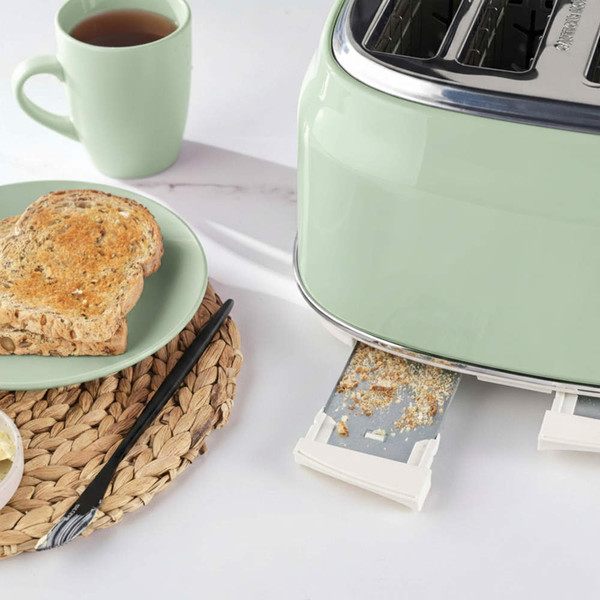 Pale green toaster with crumb tray shown, next to plate of seeded toast and mug of tea