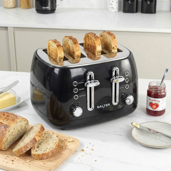 Black four-slice toaster on kitchen counter with toasted bread, loaf, butter, and strawberry jam.