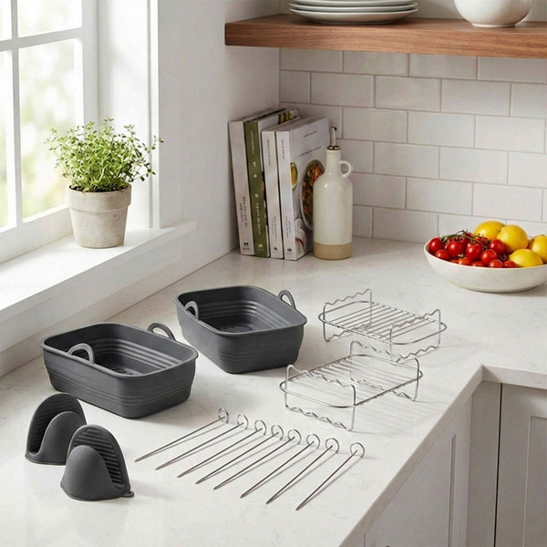 Grey roasting dishes with racks and skewers set on kitchen worktop