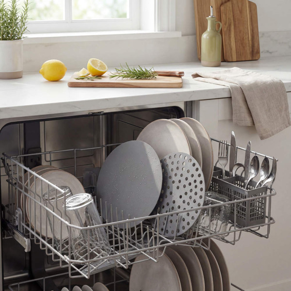 Open dishwasher with clean plates, glasses and cutlery in a modern kitchen setting