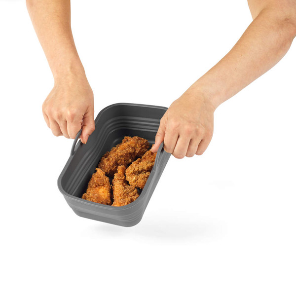 Grey collapsible food container with fried chicken pieces, held by two hands