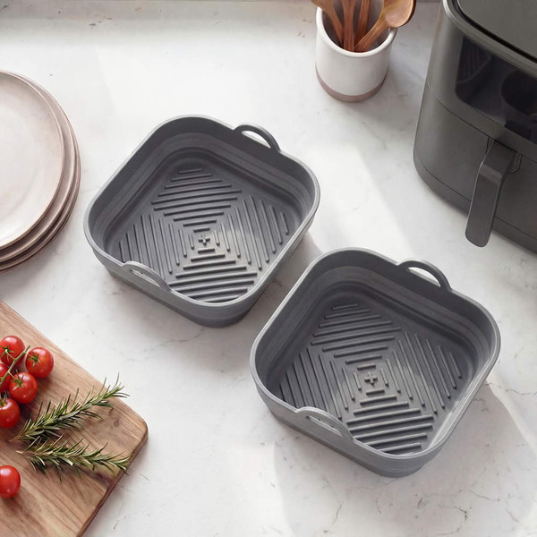 Grey silicone air fryer liners, square, set of two shown on kitchen counter