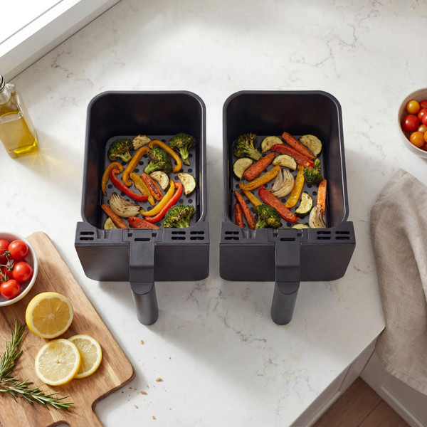 Grey dual basket air fryer on kitchen counter, filled with roasted vegetables.