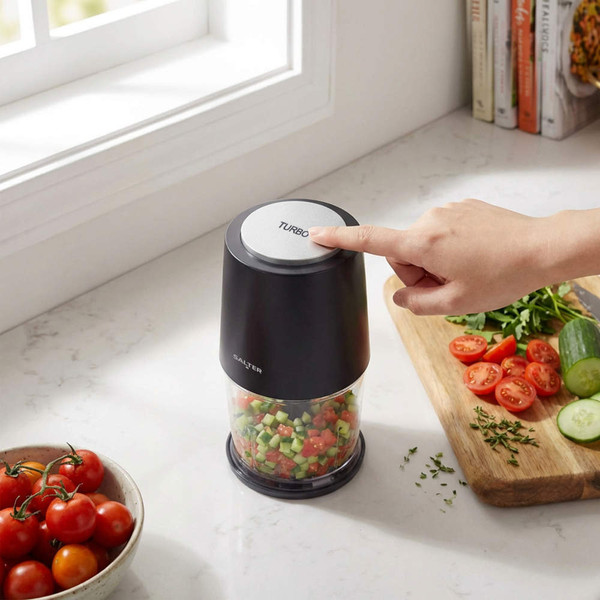 Compact electric food chopper in use on kitchen counter, dicing vegetables.