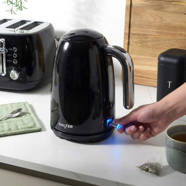 Black electric kettle being switched on in a modern kitchen setting