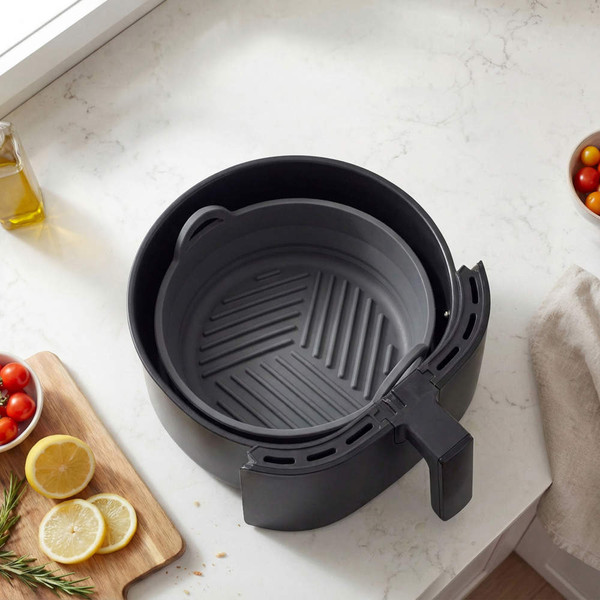 Grey air fryer basket with silicone liner on kitchen counter, top view