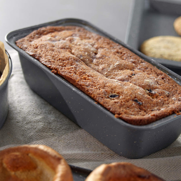 Fruit loaf cake in a non-stick loaf tin, shown fresh-baked on worktop