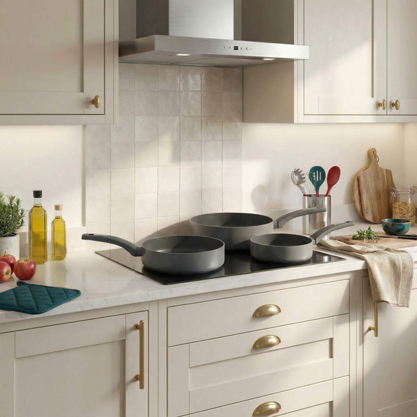Set of three grey frying pans on a modern kitchen hob, shown from above.
