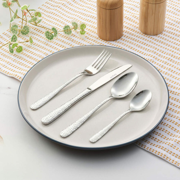 Set of four silver hammered cutlery pieces on plate