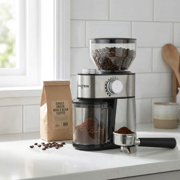 Stainless steel coffee grinder with ground coffee, whole beans, and filter handle on kitchen counter