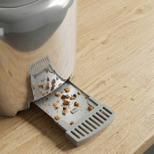 Chrome toaster crumb tray partially pulled out with crumbs visible on tray
