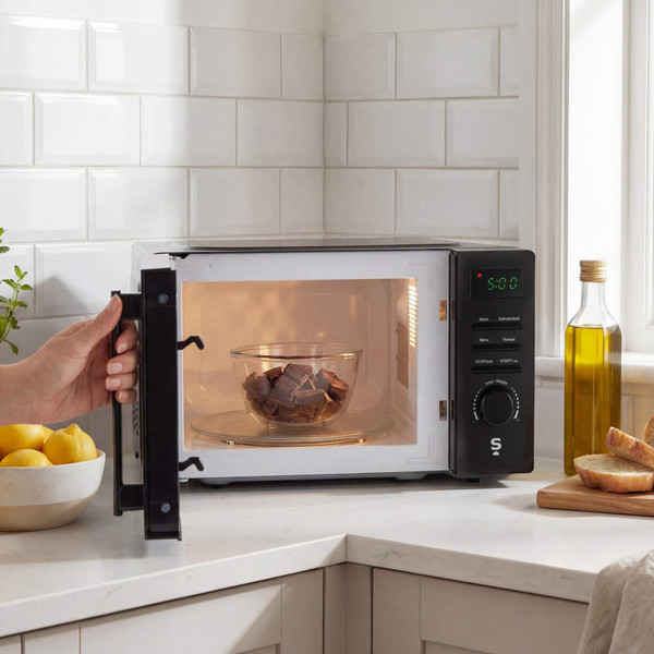 Black microwave oven on kitchen worktop near lemons, bread and olive oil