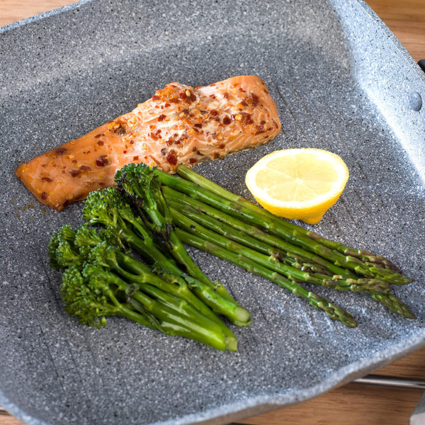 Cooked salmon fillet with chilli flakes, steamed asparagus and broccoli, lemon wedge on grill pan