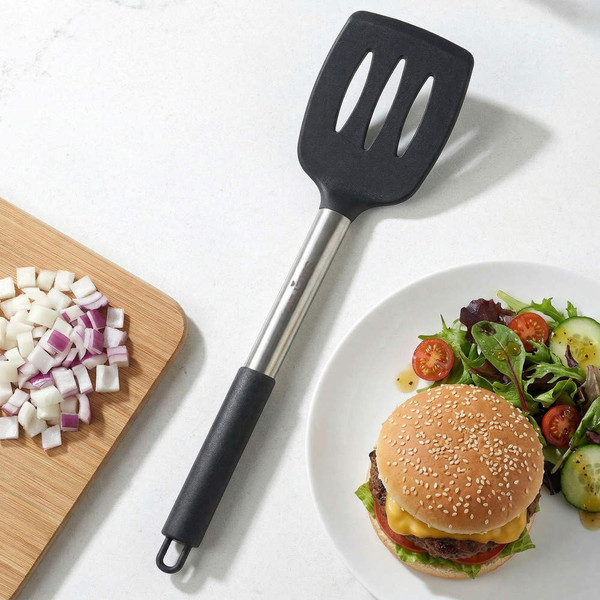 Black and silver slotted spatula next to chopped onion and cheeseburger meal
