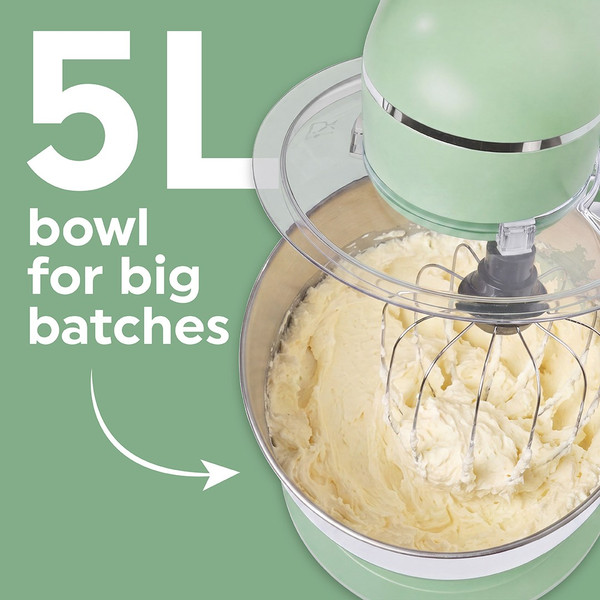 Green stand mixer with large metal bowl, person adjusting speed dial, dough hook on counter
